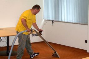 Mitarbeiter reinigt Teppichboden im Büro